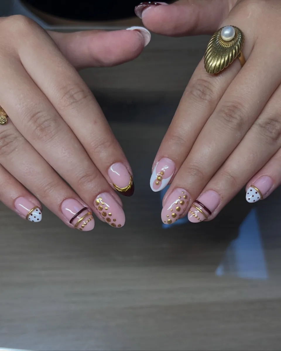 Een herfstset van VD Nails: nude amandelnagels met gouden stipjes en een bordeaux French
