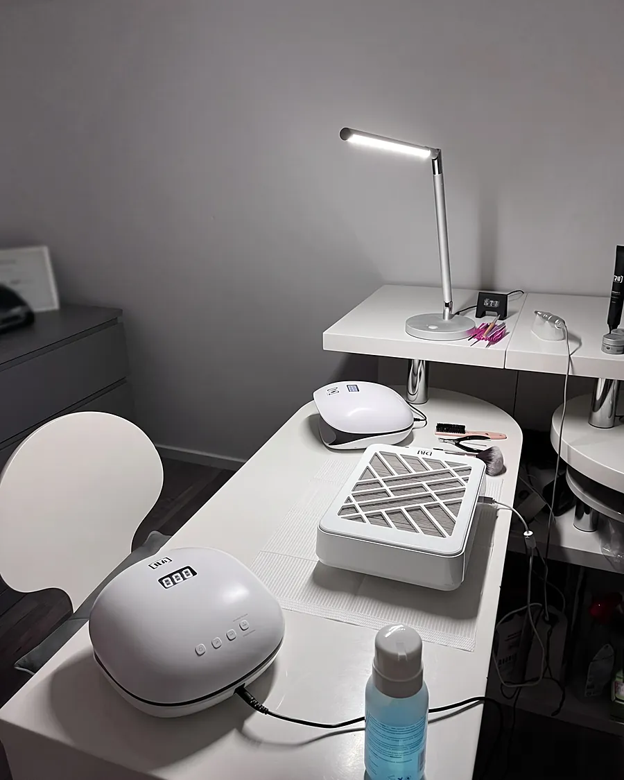 De werkplek met twee witte nagellampen, een stofafzuiger en een lamp, klaar voor de volgende klant